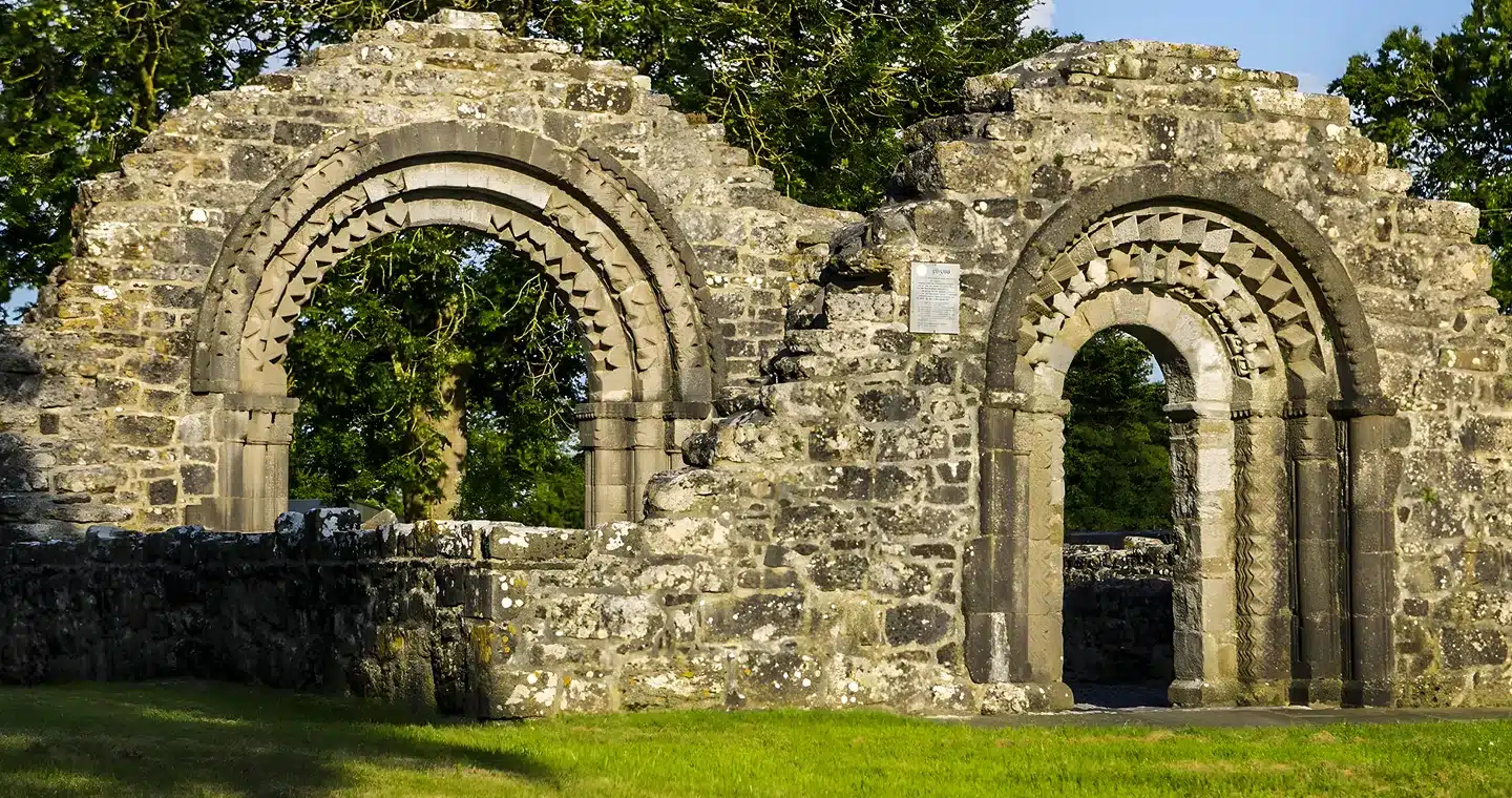 Ancient stone ruins with ornate arches, surrounded by lush greenery, highlighting Ireland’s history and beauty.
